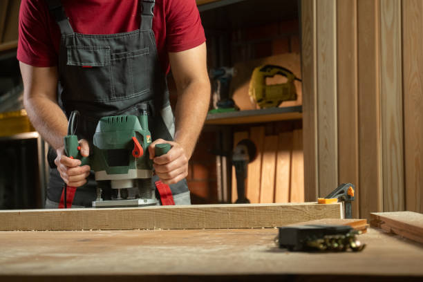 A skilled worker is using a milling machine in a cozy workshop, surrounded by wooden materials and tools. The operator carefully maneuvers the machine, showcasing precision and craftsmanship as he shapes the wood stock photo