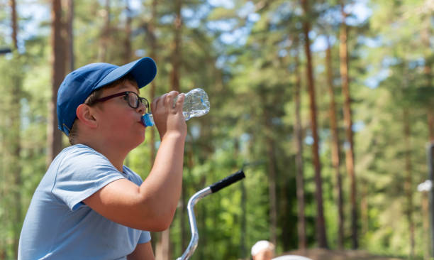 istock Boy in a blue shirt and cap drinks water after cycling 2166648331