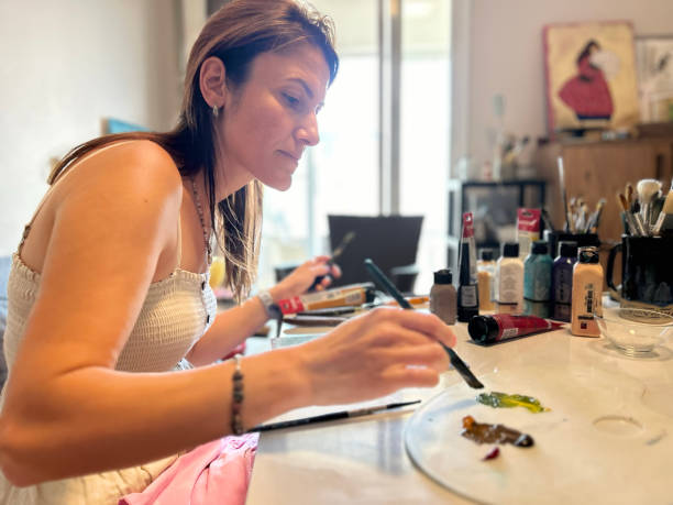 istock A close-up of a female painter working on a canvas with paints and brushes 2166654155