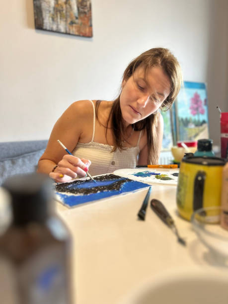 istock A close-up of a female painter working on a canvas with paints and brushes 2166654207