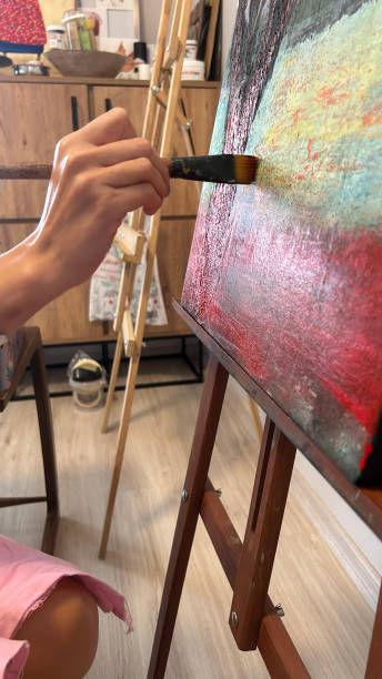 istock A close-up of a female painter working on a canvas with paints and brushes 2166654263