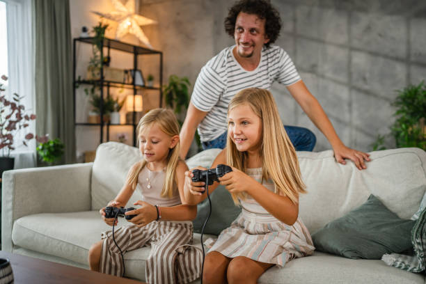istock father cheer to his daughters while they play video games on joystick 2166656204