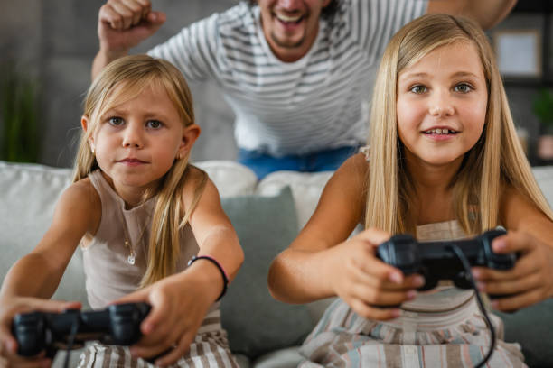 istock father cheer to his daughters while they play video games on joystick 2166657700