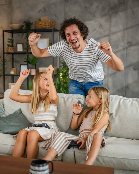 istock father cheer to his daughters while they play video games on joystick 2166657807