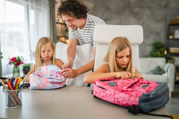 istock Single father help to his daughters to pack books in a backpack 2166659250
