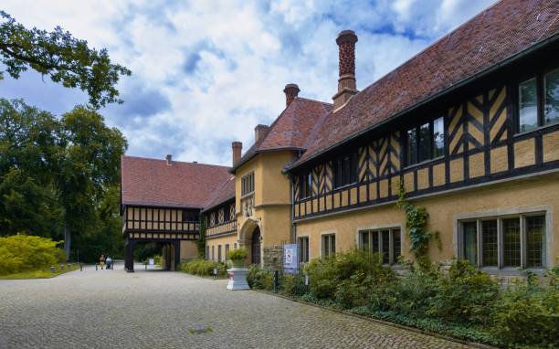 Potsdam, Germany, July 5, 2024: Two people walk along the entrance to the Cecilienhof Palace in the public park Neuer Garten  (New Garden) in Potsdam where the Potsdam Conference of the Victorious Powers took place after World War II.