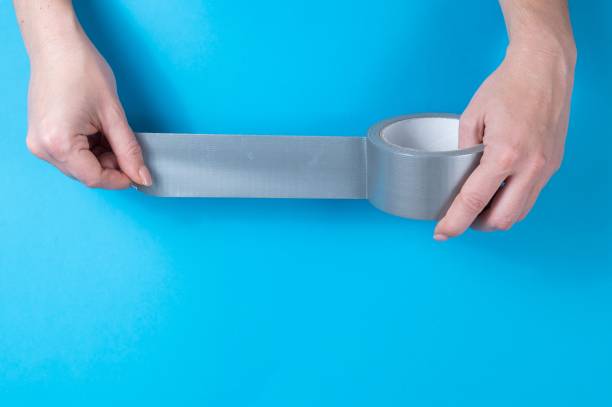 istock Woman holding silver scotch tape on blue background. 2166660441