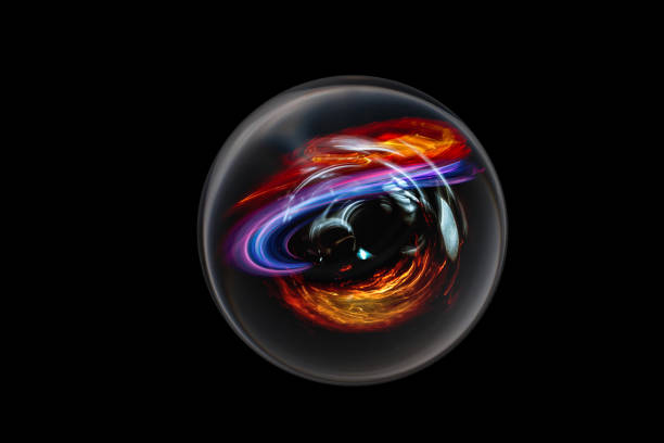 Vivid light streaks in glass orb against black background.