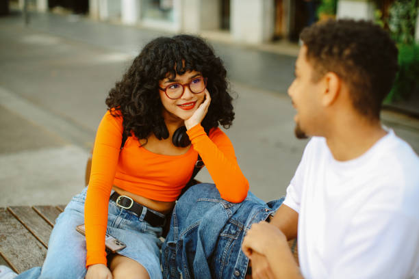 Friends spending a lovely staycation in Barcelona Young people having a nice time in Barcelona together, exploring the vibrant neighbourhood of Poblenou, relaxing at the bench in one of the small streets. flirting stock pictures, royalty-free photos & images