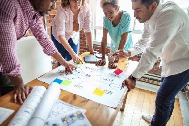 istock Multiracial colleagues in a business meeting discussing drawing diagram design plan document together 2166670929
