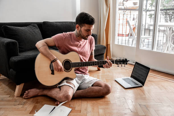 istock Young man playing guitar at home 2166671885