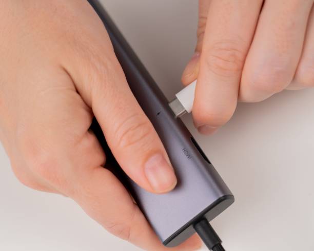 istock A woman inserts a white Type C cable into a black port. 2166672926