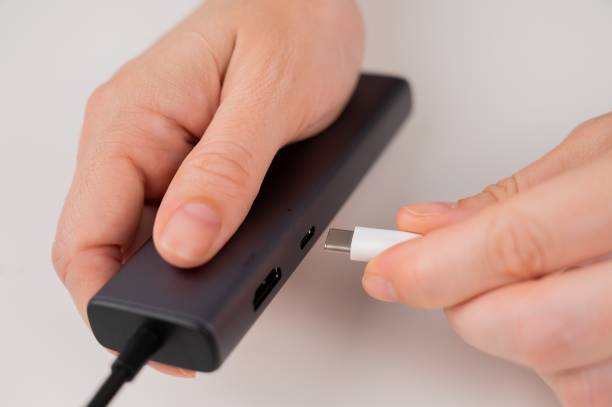 istock A woman inserts a white Type C cable into a black port. 2166672993