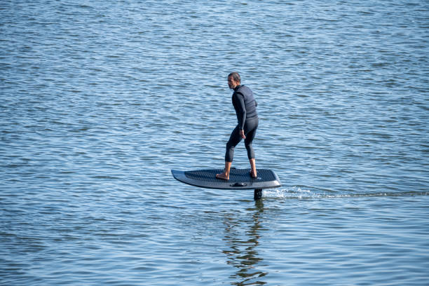 Man on an eFoil board gliding over calm blue water, showcasing balance and modern water sport technology