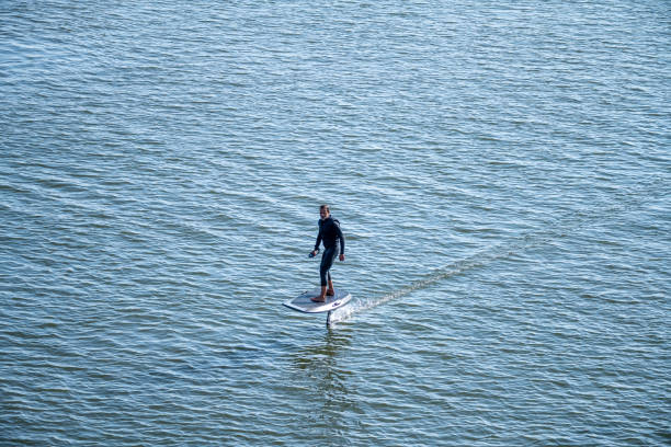 istock Man on an eFoil board gliding over calm blue water 2166673238