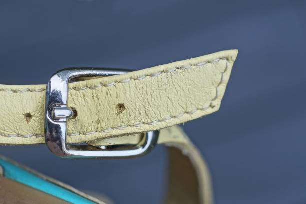 one closed gray metal clasp on a yellow leather sandal harness
