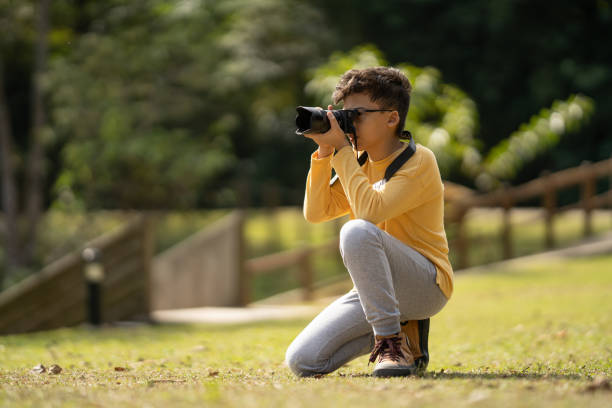 istock Boy taking picture with camera in nature 2166677079