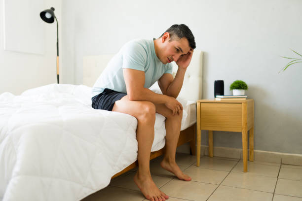 istock Latin man feeling stressed and anxious while sitting on the edge of his bed and feeling down 2166677842