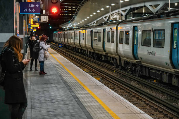 London, United Kingdom - February 02, 2019: Passengers waiting at platform at London Bridge station, empty rail tracks, lights glowing in dark night at background,
