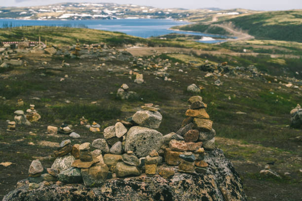 Serene Landscape with Rocky Cairns Overlooking Tranquil Lake and Rolling Hills