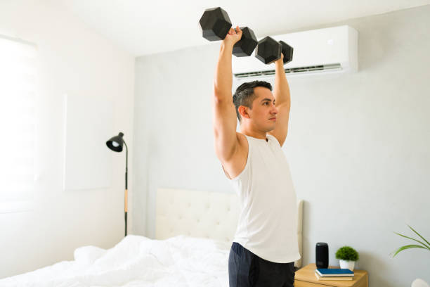 istock Latin man doing weightlifting exercises in his bedroom during a home workout session 2166686705