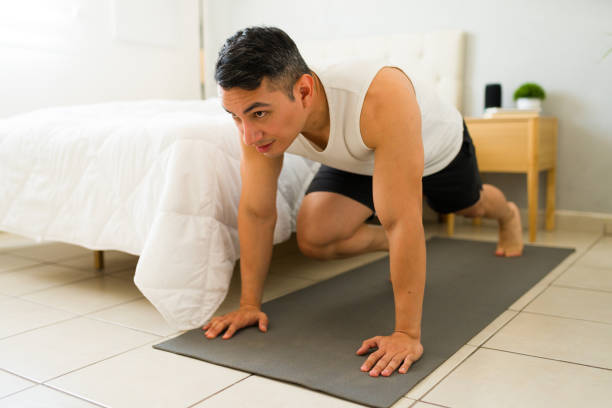 istock Strong hispanic man working out in his bedroom and doing mountain climber exercise on a yoga mat 2166686776