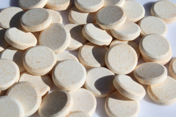 istock Group of round orange Vitamin C tablets scattered on a white surface 2166696221