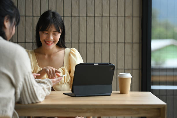 istock Cheerful young female colleagues sharing something on mobile phone while sitting in the modern cafe 2166699012