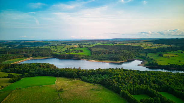 istock Aerial view of a serene lake surrounded by lush greenery and fields under a blue sky with scattered clouds in Yorkshire. 2166699094