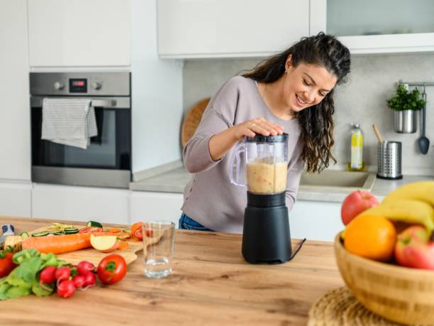 istock Woman preparing a smoothie in her kitchen at home 2166699237