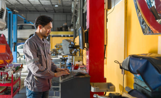 istock Young mechanic in work uniform is using a computer in an auto repair shop with tools and vehicle in the background. 2166700108