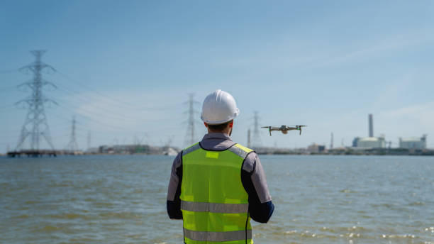 istock Engineer in a safety vest operating a drone to inspect and survey electrical power lines. Technician inspecting the power station for scheduled maintenance. 2166700911