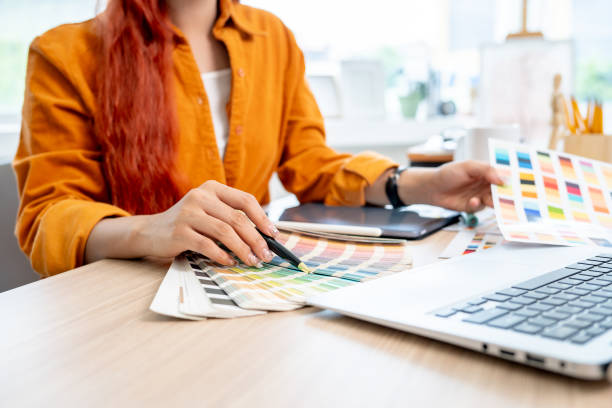 istock A female graphic designer working at her desk in the studio, selecting colors from a set of swatches 2166701007
