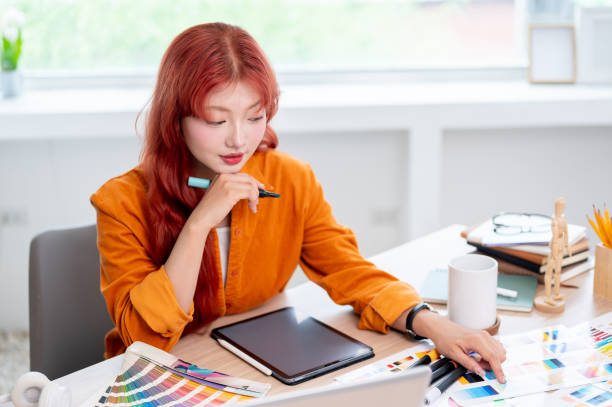 istock A creative, focused Asian female graphic designer is working at her desk in the studio. 2166701526