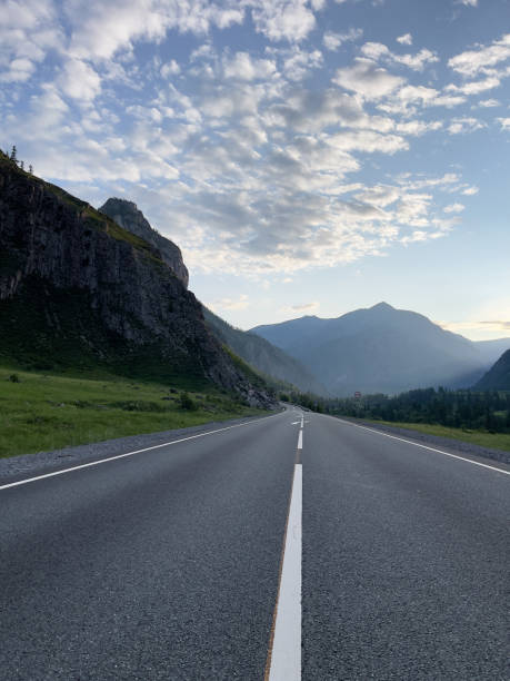 istock road in the mountains under the blue sky with white clouds and sun 2166702118