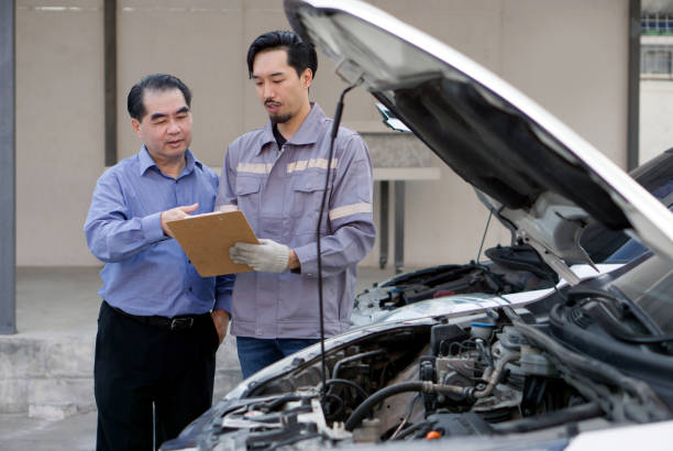 istock A mechanic in work uniform with gloves, holding document clipboard focused on the paperwork. The car owner or a service advisor discussing the vehicle's issues or maintenance work with the technician 2166702486