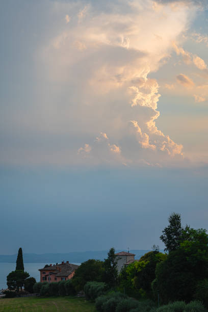 Tall thunderstorm towers high above a hazy layer near Lake Garda, Italy.