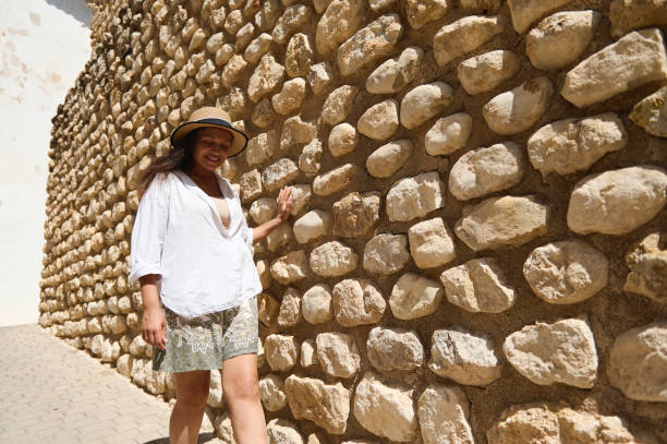 istock Woman enjoying sunny day strolling along rustic stone wall 2166703869