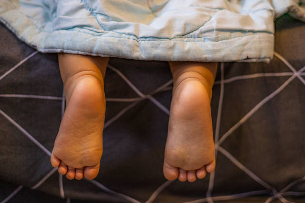 Legs of child sticking out from under the blankets.