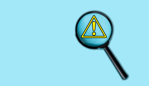 istock Magnifying Glass Highlighting Warning Symbol on Light Blue Background 2166707170