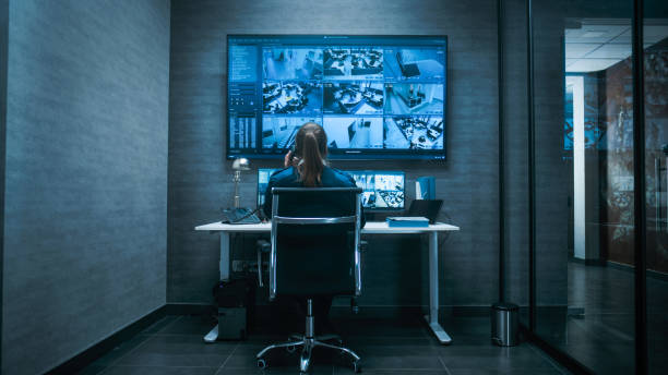 istock Female CCTV operator watches security cameras on multiple monitors and digital screen 2166716130