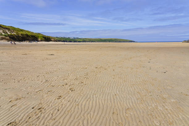At low tide footprints in the rippled sands of Crantock beach lead towards the distant sea.