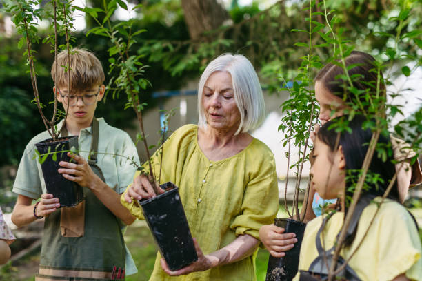 istock Kids learning about fruit tree seedling and fruit bushes, taking care of school garden during outdoor sustainable education, class in forest school. Concept of experiential learning and ecoliteracy. 2166719942