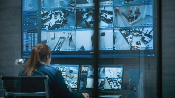 istock Female CCTV operator works on computer with security cameras, talks on walkie talkie 2166720930