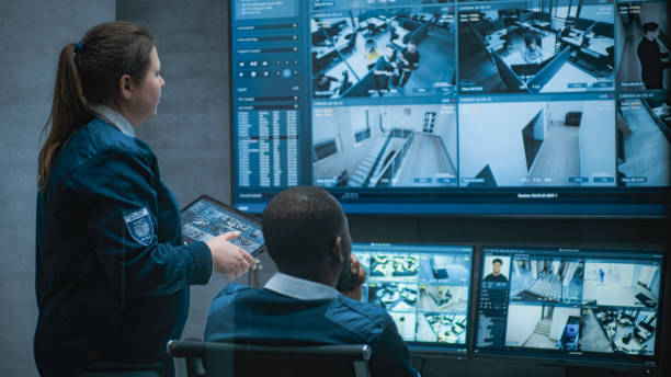 multiethnic cctv operators control security cameras on computer and tablet - beveiliger stockfoto's en -beelden