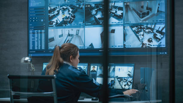 istock Female CCTV operator works on computer with security cameras, talks on walkie talkie 2166722442