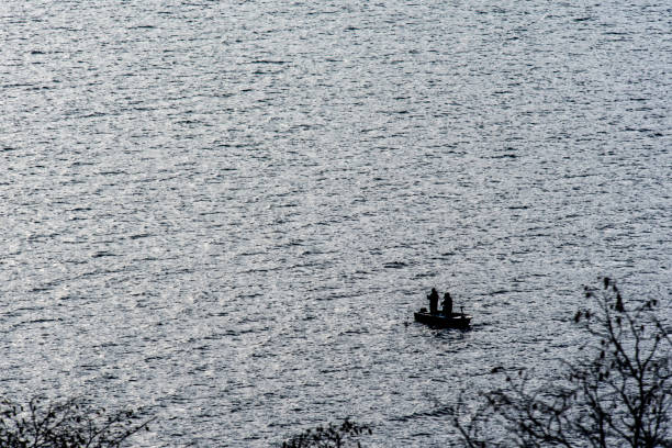 small boat with fishermen in Lecco lake in winter in Lecco in Italy
