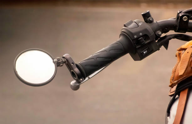 istock Close-up of a motorcycle handlebar grip with a round mirror attached. The grip has a textured surface and the controls are visible. 2166726896