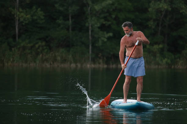 istock Senior bearded man surfing on SUP board 2166730035
