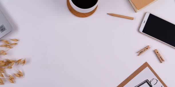Office desk with empty place on paper, smart phone with device sreen and black coffee cup. Office supply on white background. Place of work. Web banner.